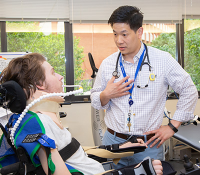 Wesley Chay, M.D., visits with a patient in the Comprehensive Rehabilitation Unit. 