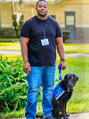 Facility dog, Poet III, sits with his handler Derrick Gates.