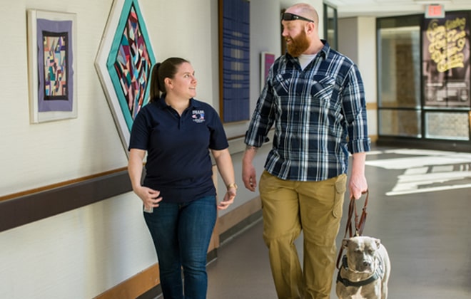 SHARE patient Garland Ellison walks with staff member down hallway at Shepherd Center