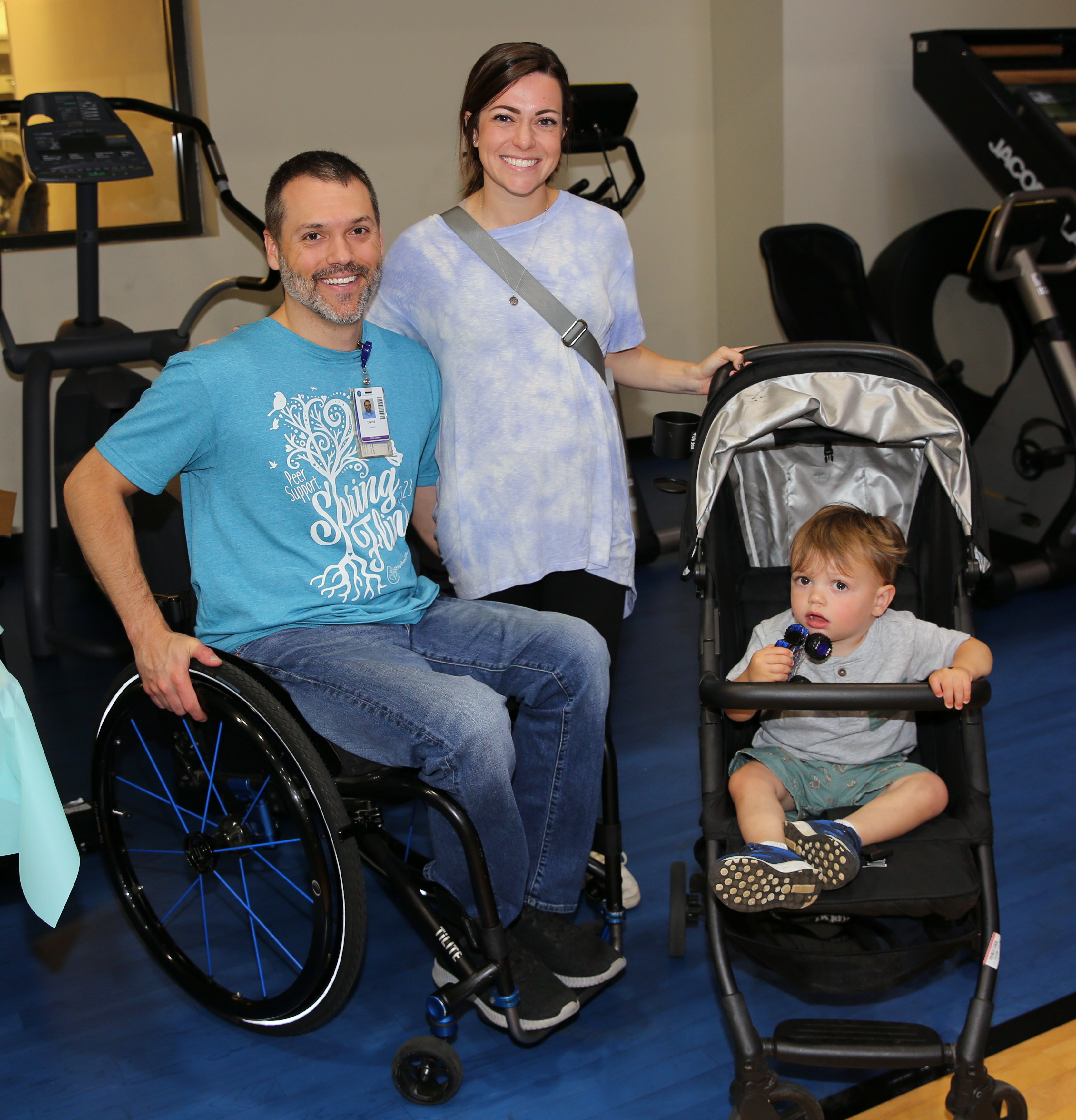 Man in wheelchair with woman and their child in a stroller at a peer support community function