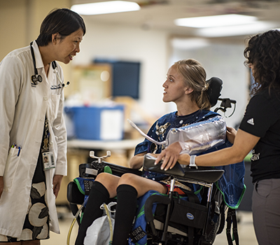Caroline Moore, a patient, talks with Dr. Anna Elmers and exercise physiologist Elizabeth Pena.