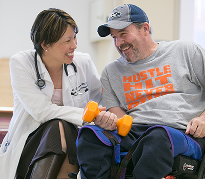 Shepherd Center physiatrist Anna Elmers, M.D., works with spinal cord injury patient Andy Collier in a rehabilitation therapy gym. 