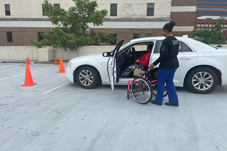 Occupational therapist and certified driver educator, Lakisha Gray, assists Egypt Lundy into her wheelchair as she exits the car following a driving practice session.