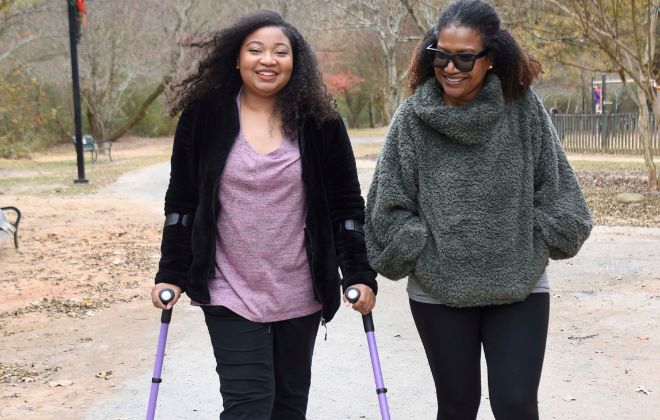 MS wellness patient walks with poles for balance outside in park with mom