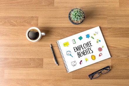 Desk with coffee cup, plant and notebook with the words &quot;Employee Benefits&quot;