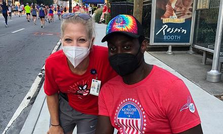 A man and woman wearing face masks pose for a picture at the AJC Peachtree Road Race