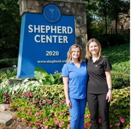 Former PGY1 Pharmacy Residents smile while standing in front of Shepherd Center sign