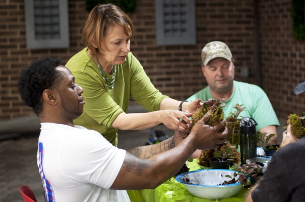 Instructor assists two SHARE military clients with plant care at Shepherd Center’s greenhouse