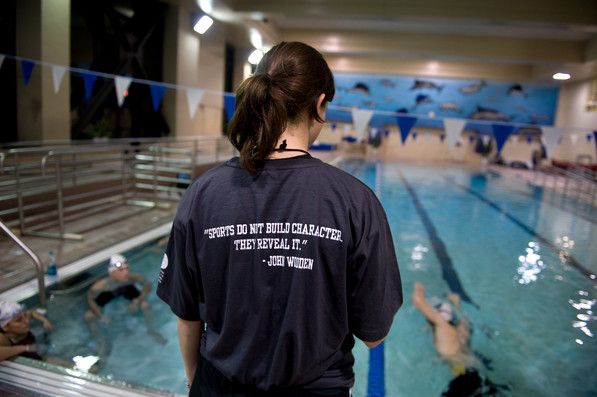 A person by a pool with the phrase, “Sports do not build character. They reveal it” on her shirt