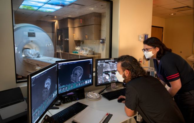 Two care providers examine imaging scans of skull on a computer as part of imaging services