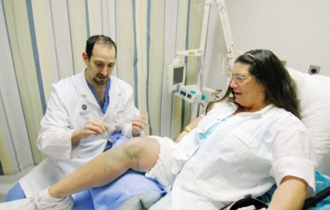 A Pain Institute physician applies a chronic pain treatment to a patient's knee while she is seated