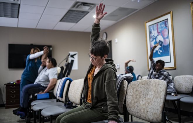 MS Wellness members lean to side with arms extended as they participate in chair yoga