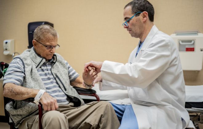 Allan Peljovich, M.D., examines patients hands in the Upper Extremity Clinic at Shepherd Center