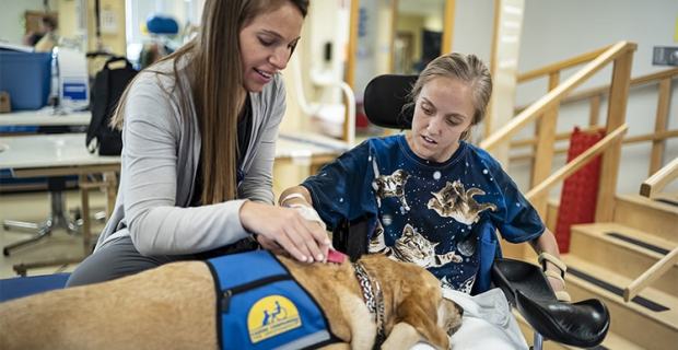A patient with a spinal cord injury has therapy with a facility dog.