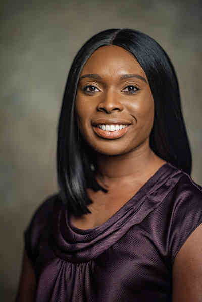 Headshot of Aiwane Iboaya, D.O., smiling from the shoulders up wearing a purple top